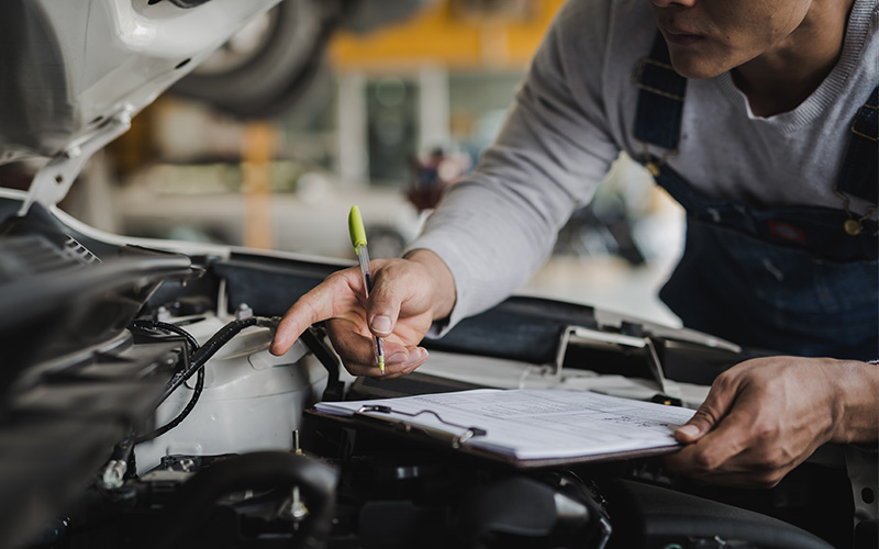 GMC certified mechanic following a checklist to inspect engine of an SUV